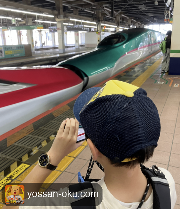 駅のホームで連結した新幹線を撮影する小学生の息子